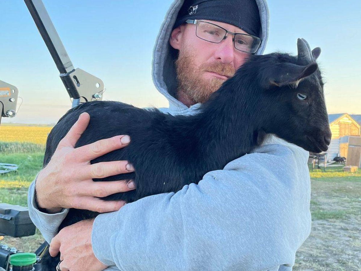 Chris McKenzie holding a baby goat at Bacon N Egg Ranch